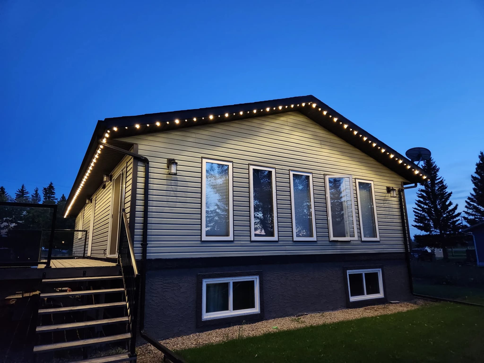 Home at twilight outlined in warm-white permanent LED track lighting