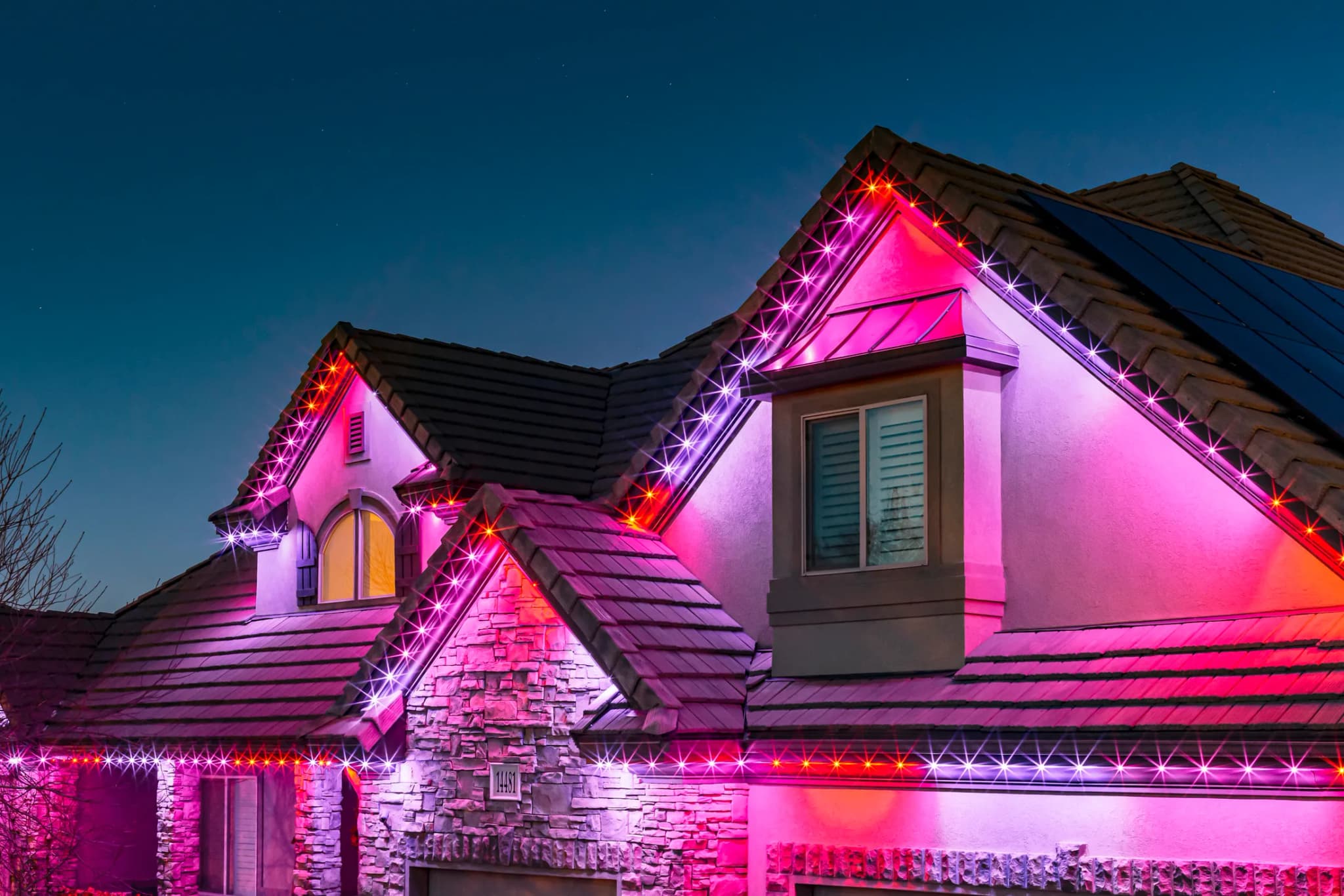 Home exterior lit with warm permanent LED lighting along the roofline and garage